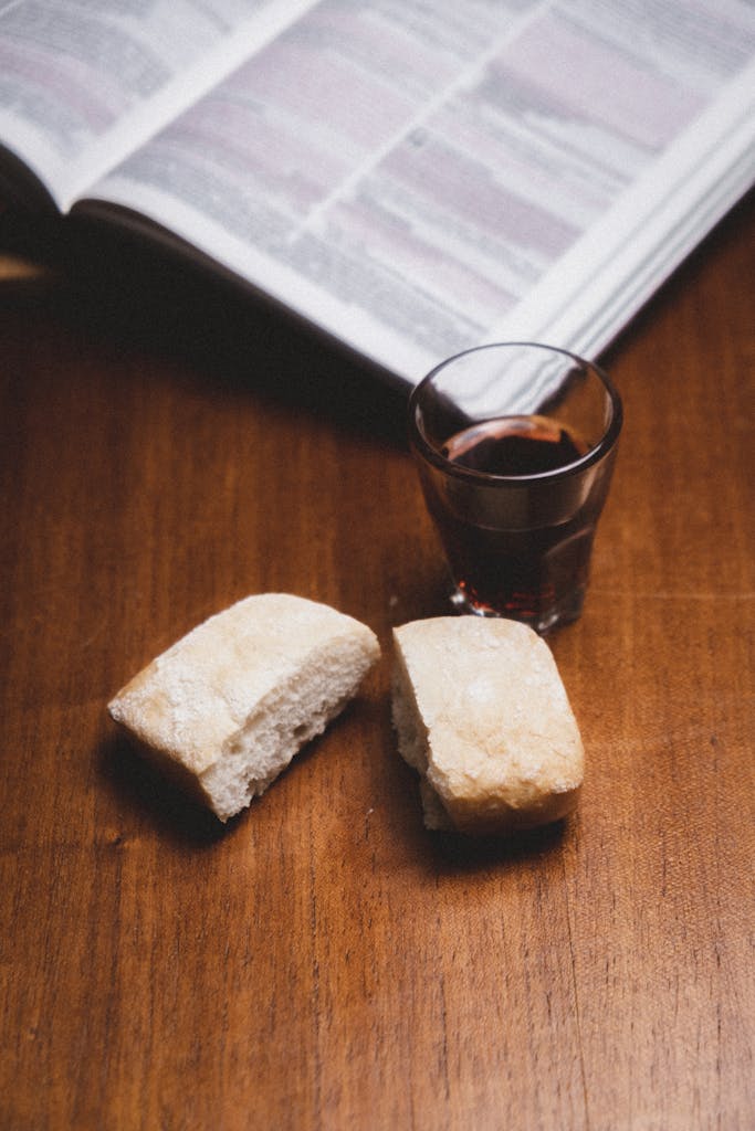 A cozy still life featuring bread and red wine on a table with an open book.